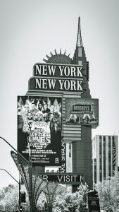 Black and white photo of the New York New York Hotel sign in Las Vegas showcasing a comedy tour poster.