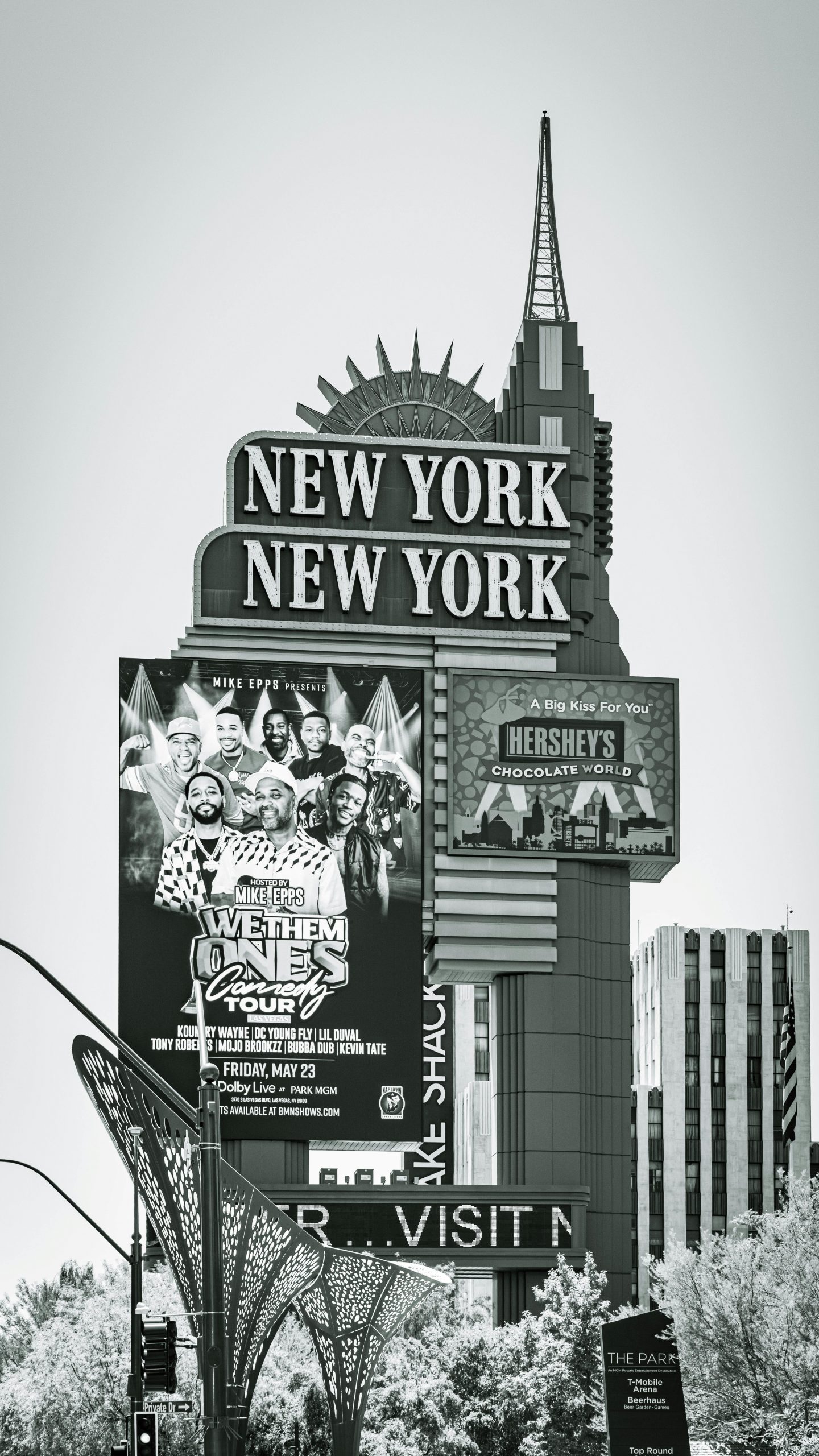 Black and white photo of the New York New York Hotel sign in Las Vegas showcasing a comedy tour poster.